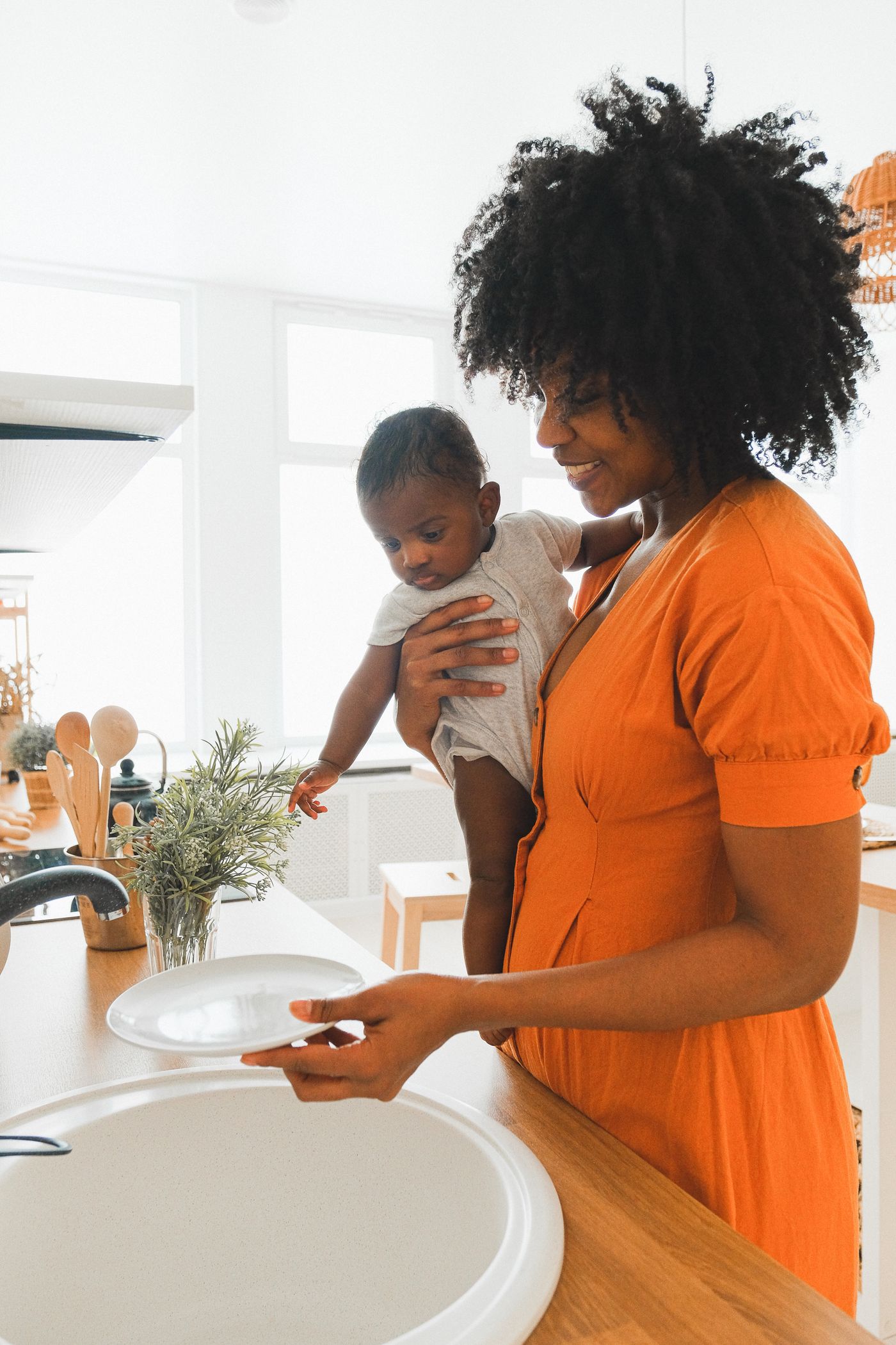 Une femme noire tenant un bébé dans une cuisine lumineuse