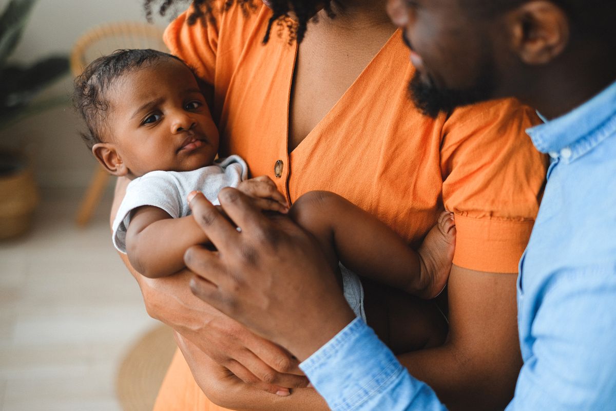 Parents holding a baby indoors in warm light