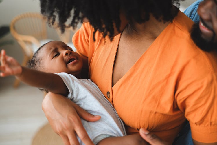 An Afro-Haired Woman Carrying A Baby