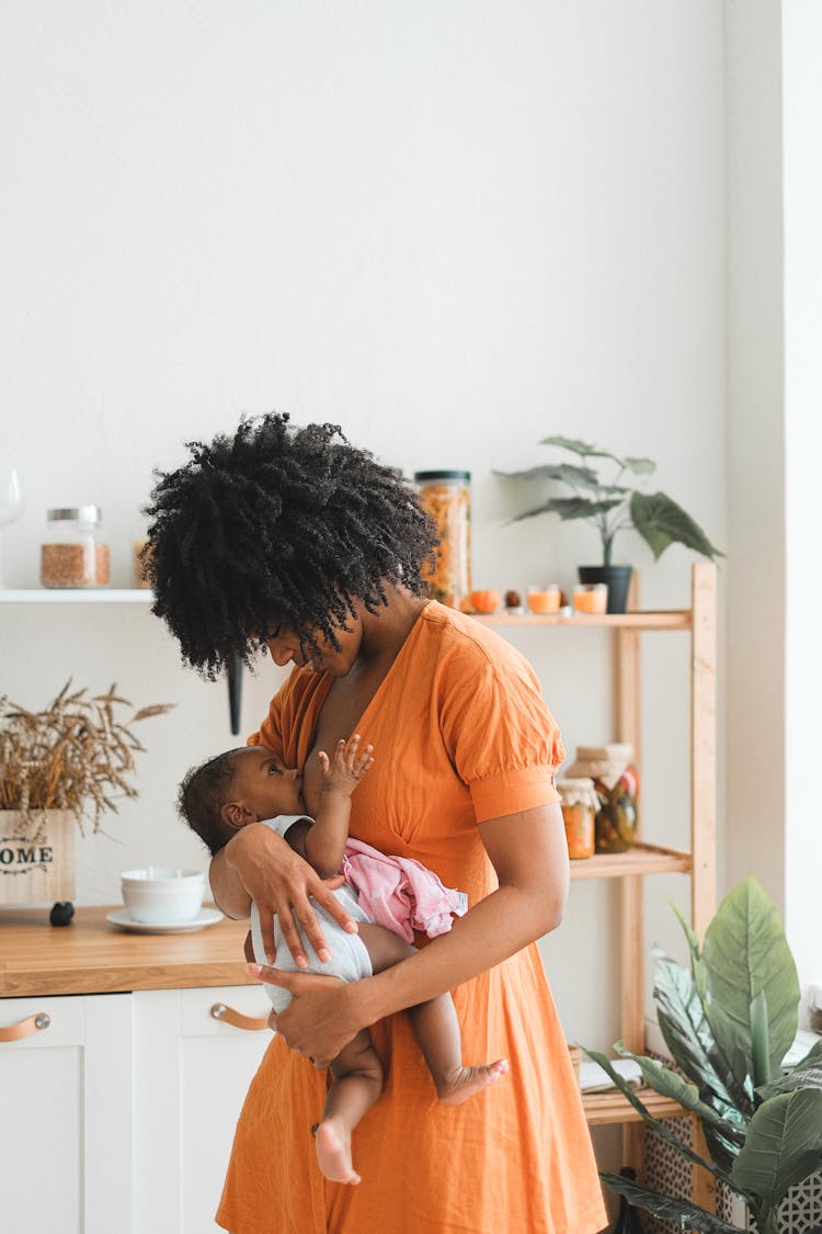 An Afro-Haired Woman Carrying A Baby