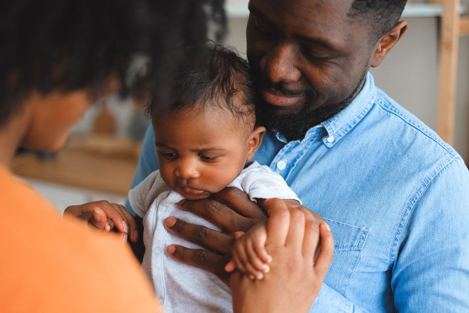Parents sharing a loving moment while holding their baby at home.