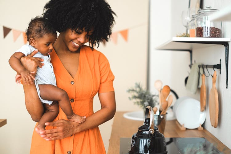 An Afro-Haired Woman Carrying A Baby