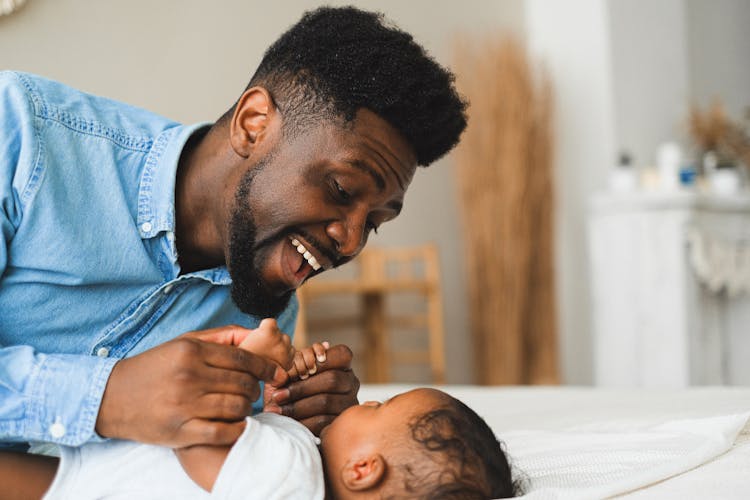 A Man In Blue Long Sleeves Playing With His Baby