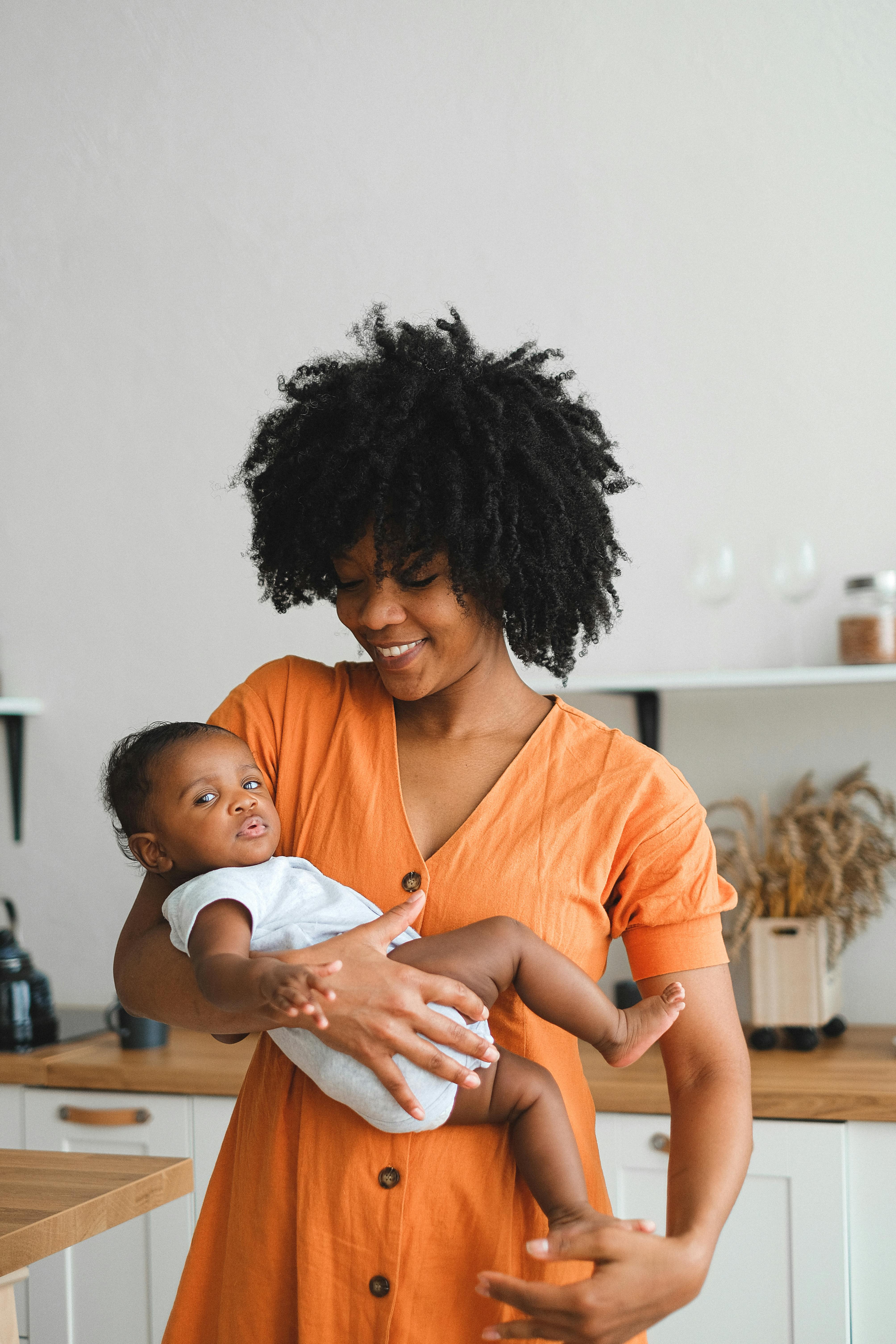 an afro haired woman carrying a baby