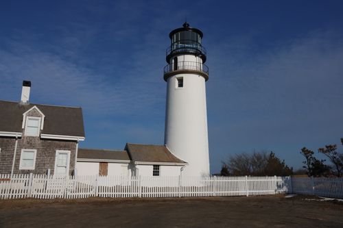 Free Classic Cape Cod lighthouse at sunrise in Truro, MA, with white picket fence and clear sky. Stock Photo