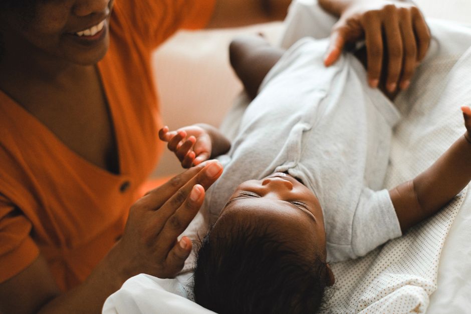 A heartwarming moment of a mother engaging with her newborn baby indoors, showcasing love and connection.