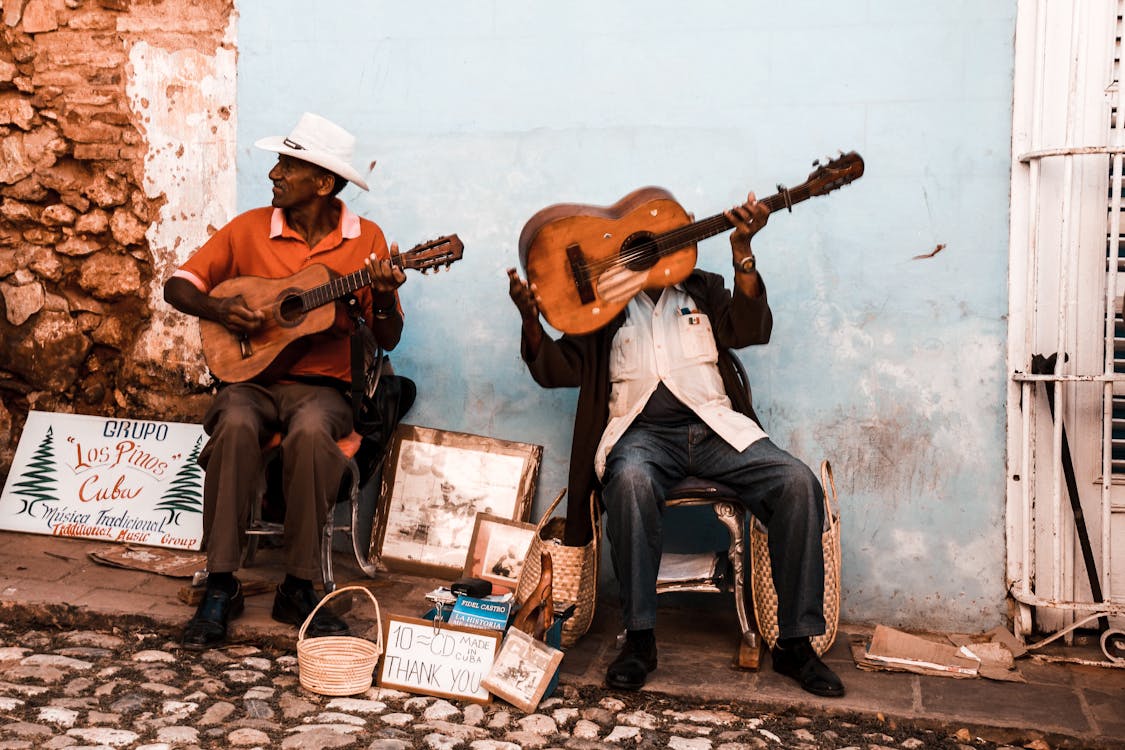 Men Sitting on Chairs Playing Brown Guitars
