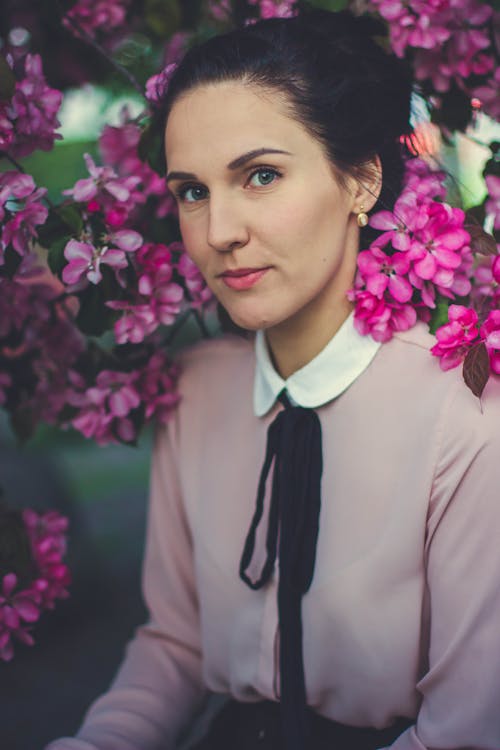 Femme Portant Une Chemise à Manches Longues à Col Rose Et Blanc Sous Une Fleur Pétale Rose En Fleurs