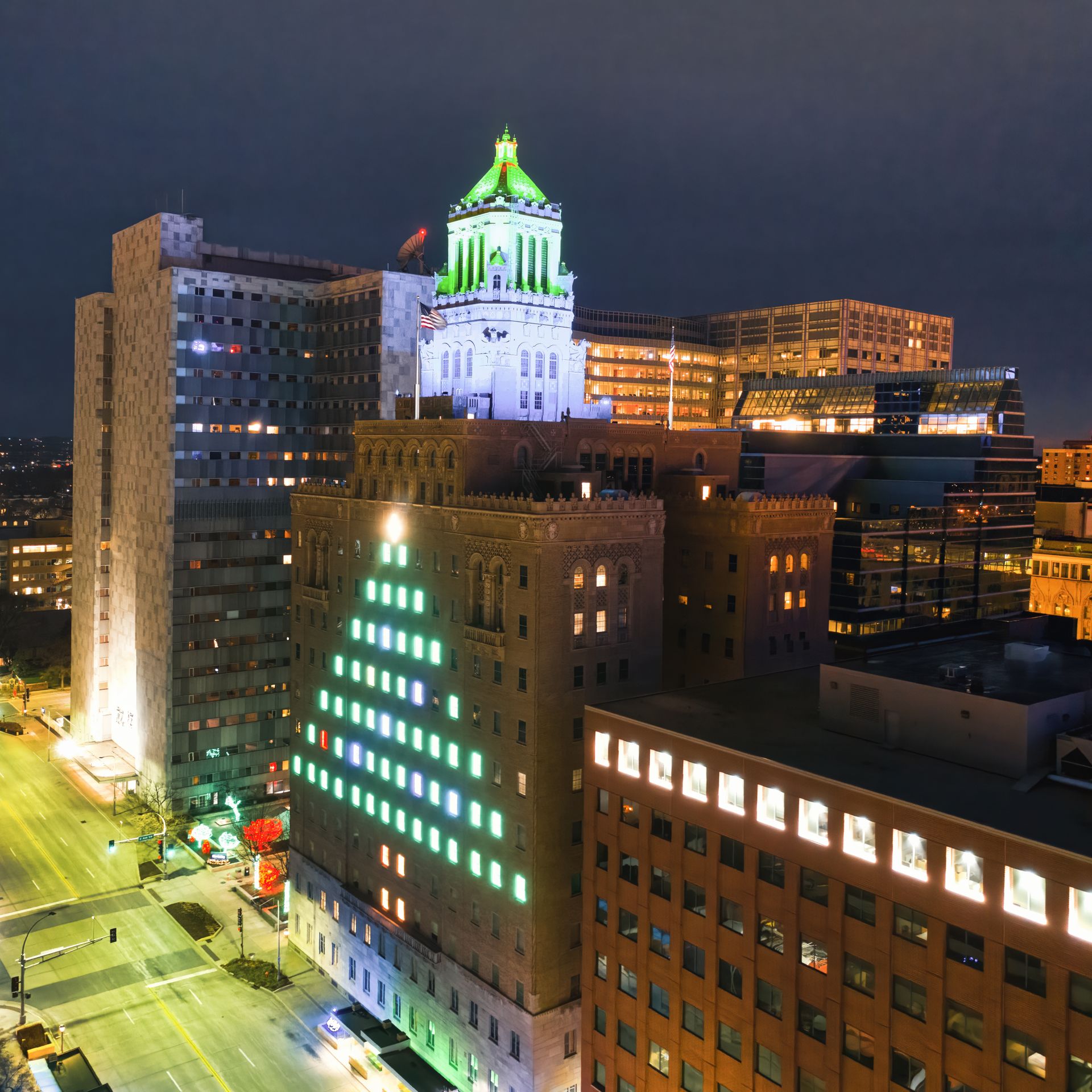 Night aerial view of downtown Rochester, MN showcasing the illuminated Plummer Building and city skyline.