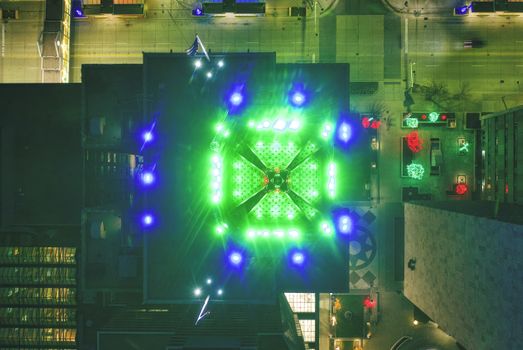 Drone shot of a building with green and blue lights illuminating the night in Rochester, MN.