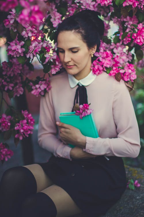 Woman Wearing Beige Long Sleeve Shirt Sitting Beside Purple Petaled Flower