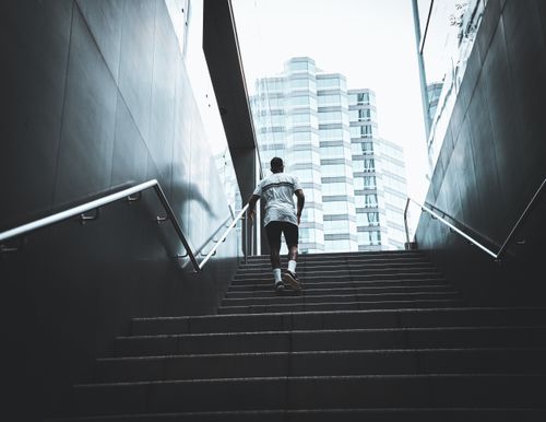 Free A person climbs outdoor stairs in Perth, against a modern city backdrop. Stock Photo