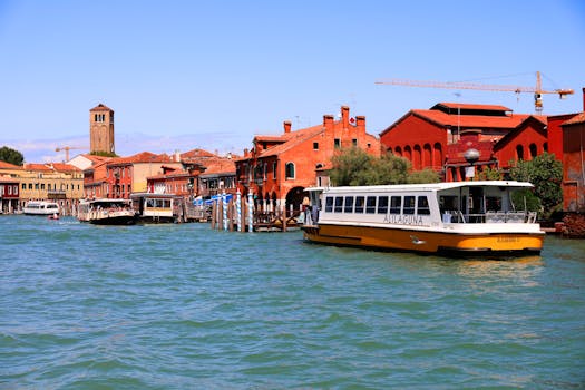 Colorful Venetian canal with watercraft and historic buildings under clear blue skies.