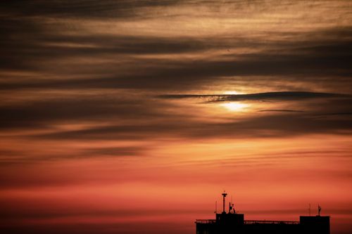 Free Stunning view of sunset skies over a building silhouette, offering a serene twilight ambiance. Stock Photo
