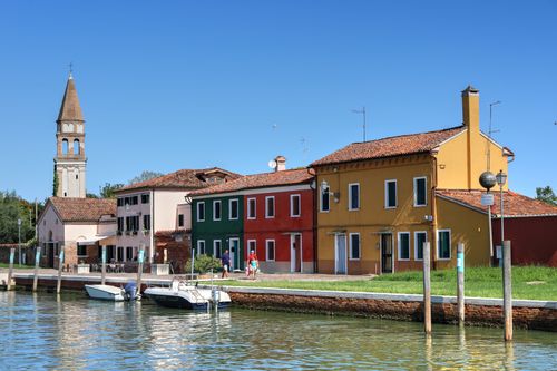 Free Vibrant houses line a canal in Burano, Venice under clear summer skies. Stock Photo