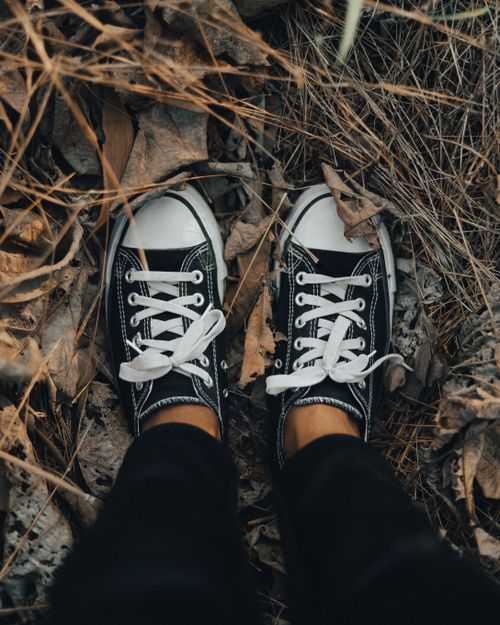 Free Top view of black sneakers on dried grass and leaves, conveying autumn vibes in Palghar, India. Stock Photo