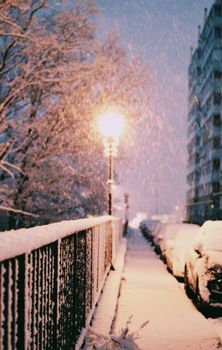 A snowy street scene with a glowing lamp post during twilight, capturing the essence of winter.
