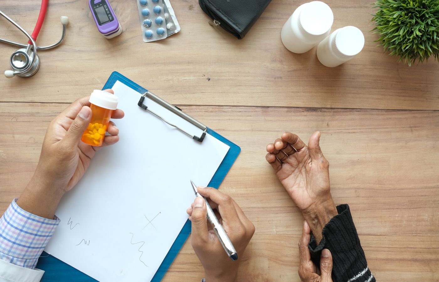 A doctor holds a pill bottle while consulting with an elderly patient. A stethoscope and prescriptions are visible.