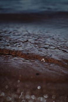 Detailed close-up of gentle ocean waves lapping at a sandy beach, capturing the tranquil seaside ambiance.
