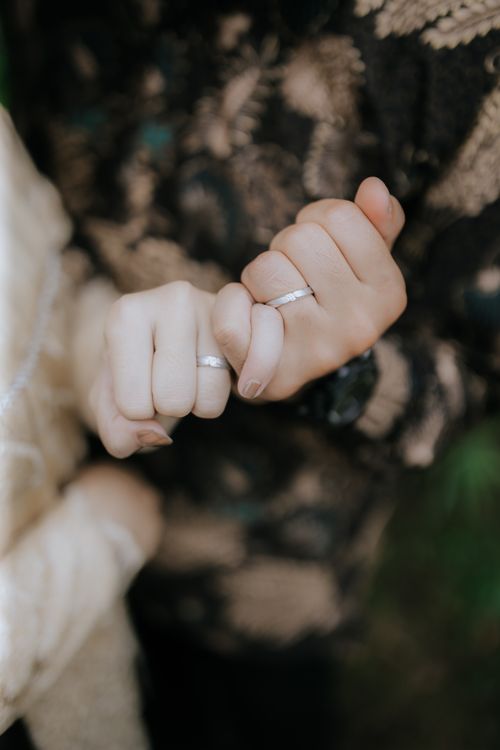 Free A close-up of a couple's hands making a pinky swear, showcasing their wedding rings. Stock Photo