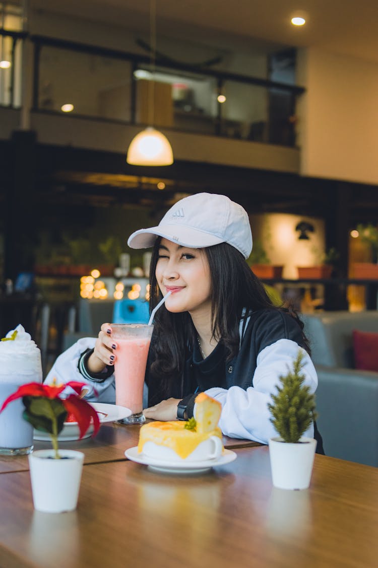 Woman In White Baseball Cap Drinking Smoothie 