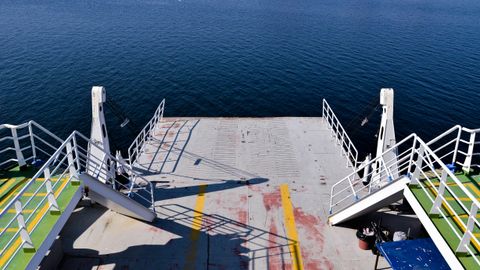 An empty ferry deck overlooking the calm ocean on a sunny day.