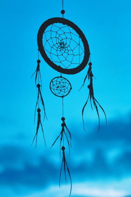 Free Beautiful silhouette of a dreamcatcher hanging against a clear blue sky, creating a peaceful ambiance. Stock Photo