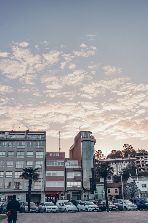 Free A picturesque sunset view of the urban skyline in Sada, Galicia, featuring modern buildings and parked cars. Stock Photo
