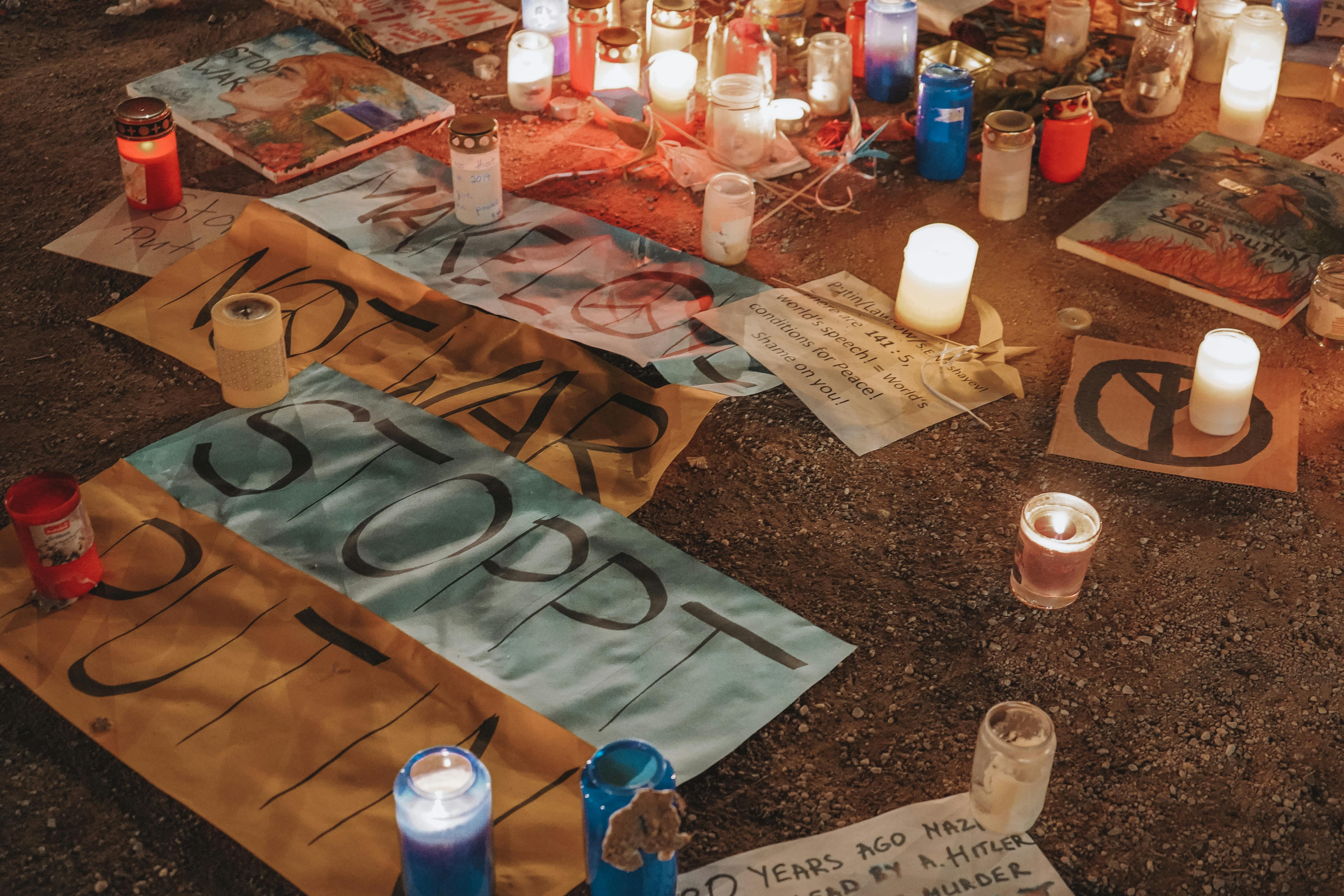 Vigil in Berlin with candles and protest signs against war, highlighting peace efforts.