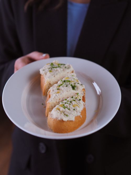 Free Sliced bread with creamy topping garnished with herbs, elegantly presented on a plate. Stock Photo