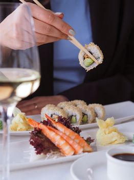 Close-up of a hand using chopsticks to enjoy delicious sushi in a refined setting.
