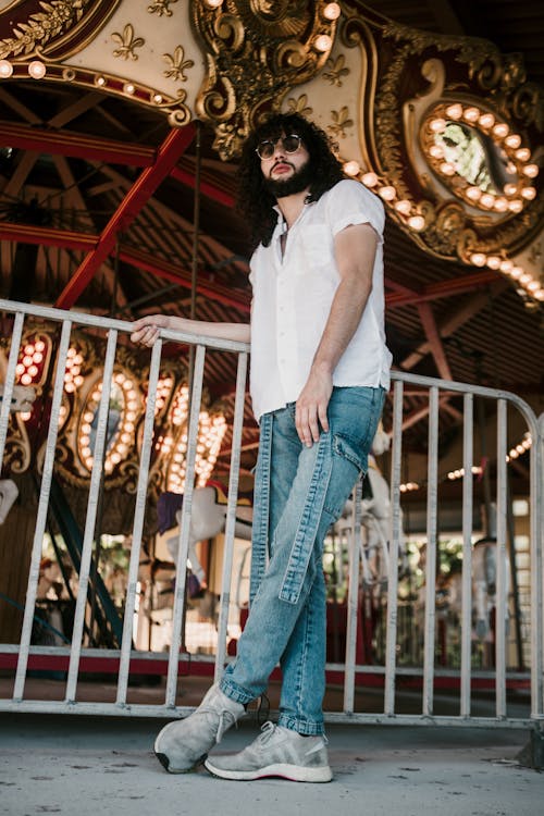 Young Man in White Short Sleeved Shirt Standing Beside a Carousel