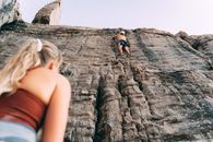 Woman and Man Climbing Up a Rocky Wall