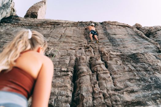 Woman and Man Climbing Up a Rocky Wall