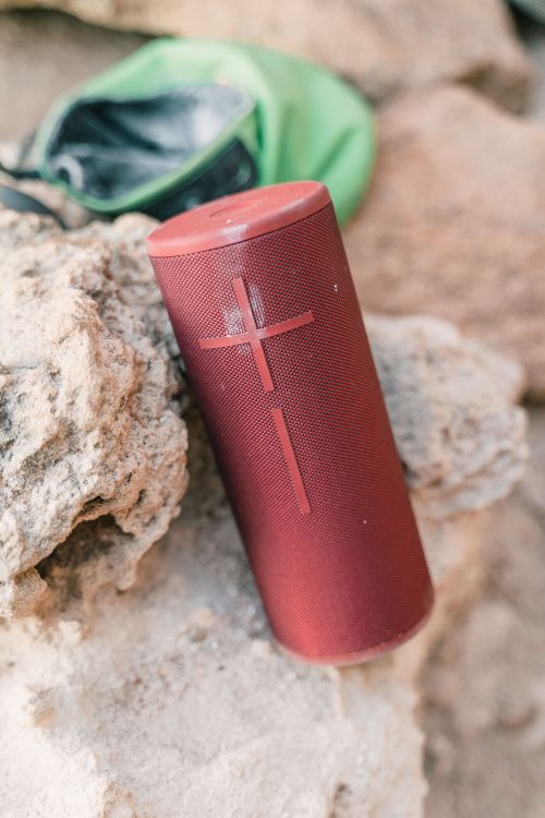 Free Close-up of a red portable wireless speaker placed on rocks, ideal for outdoor adventures. Stock Photo