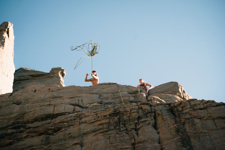 A Person Throwing Rope Over A Natural Rock Formation