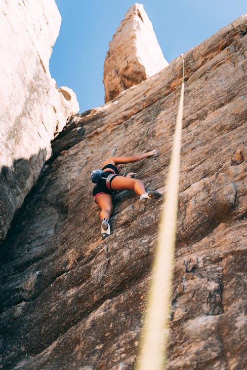 Free Low Angle Shot of a Woman Climbing a Natural Rock Formation Stock Photo