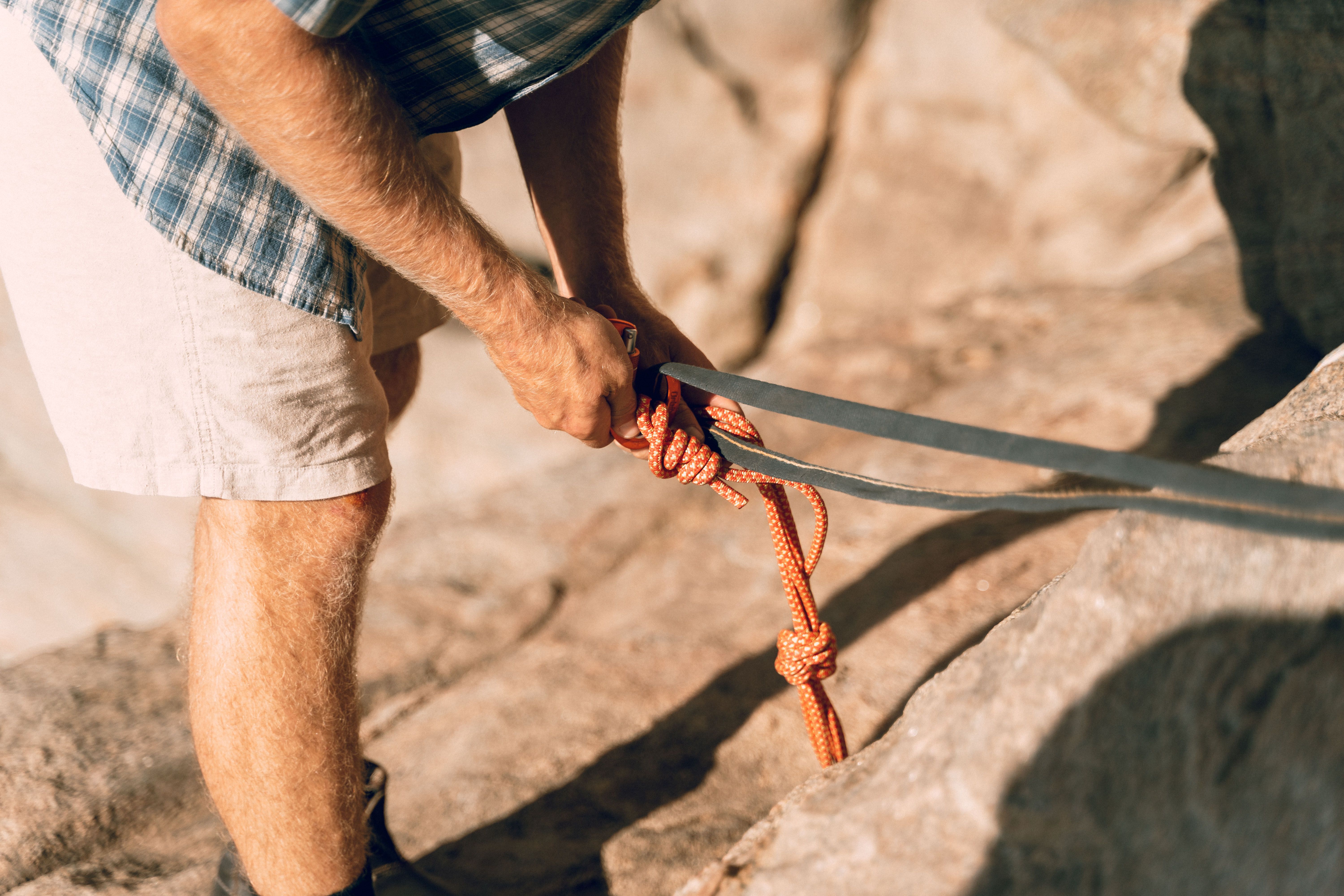 Close-up of a man securing climbing rope outdoors. Perfect for adventure themes.