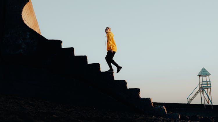 A Young Man In A Trendy Outfit Walking Up The Stairs