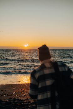 A person watches the breathtaking ocean sunset with soft reflections on the shore.