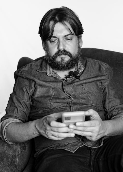 Black and White Photo of Bearded Man Holding a Cellphone