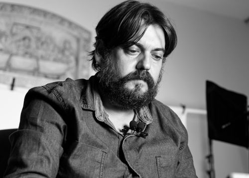 Free A serious bearded man in a denim shirt, captured in a moody black and white setting. Stock Photo