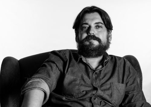 Free Black and white close-up portrait of a bearded man sitting comfortably in an armchair. Stock Photo