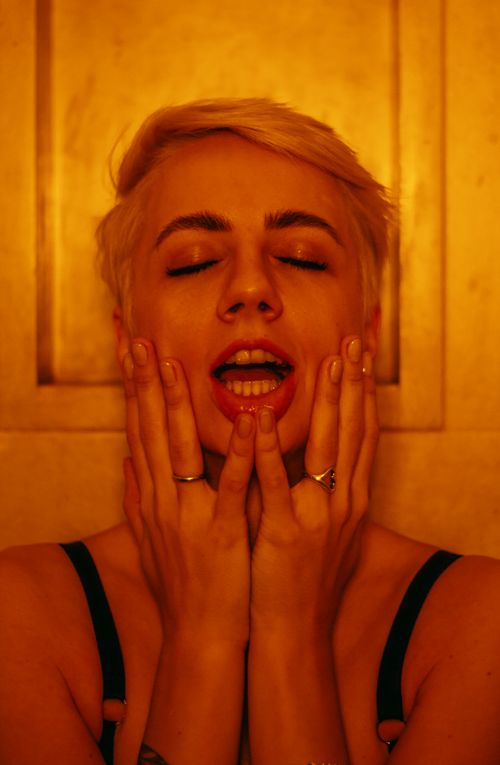Free Close-up portrait of a woman with short hair expressing joy, hands on face. Stock Photo