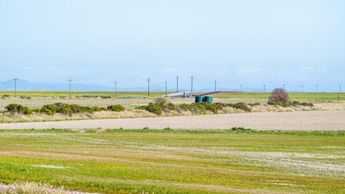 Free A vast open field with green pastures and distant hills under a clear blue sky. Stock Photo
