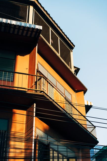 A vertical shot of a building with balconies in sunlight, showcasing urban architecture.