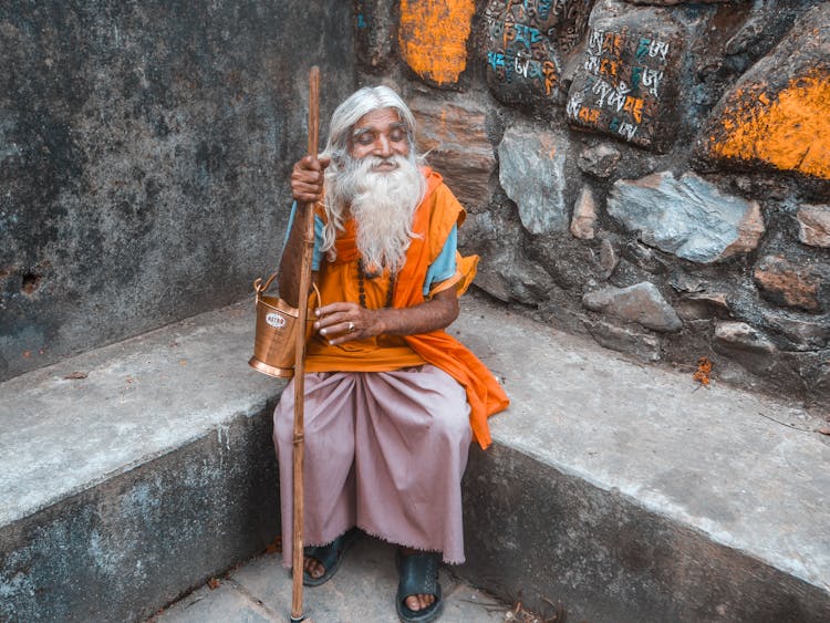 A Man Sitting With A Stick