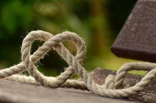 Free Brown Rope Tangled and Formed Into Heart Shape on Brown Wooden Rail Stock Photo