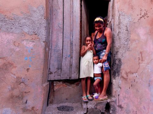 Free Family standing in a rustic doorway with colorful walls, capturing a candid moment. Stock Photo