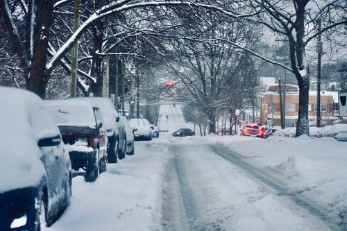 Free Snow-covered street lined with parked cars and leafless trees, depicting a serene winter cityscape. Stock Photo